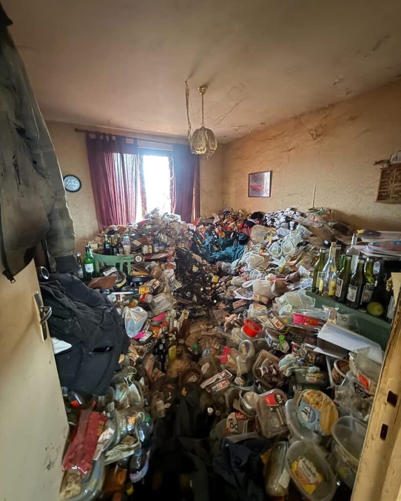 Intérieur d'une chambre encombrée de détritus, emballages alimentaires et bouteilles vides. Syndrome de Diogène.